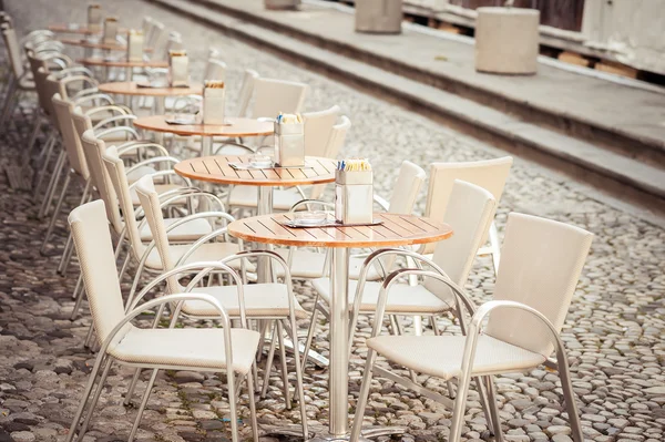 Row of little tables with chairs  in open cafe