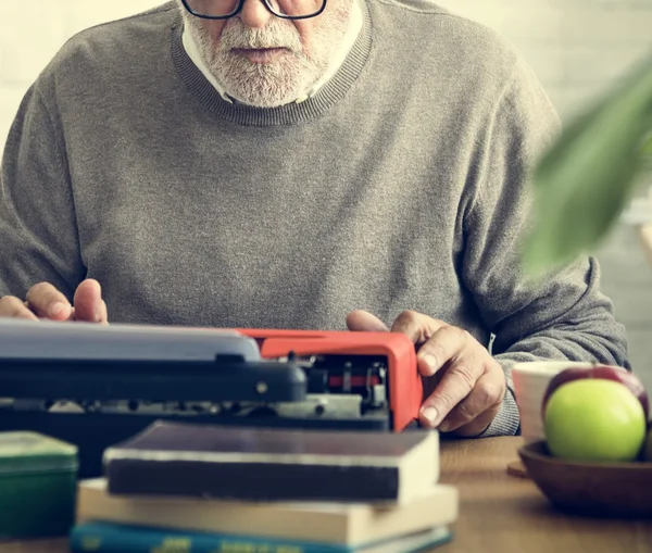 Senior man writing on typewriter machine