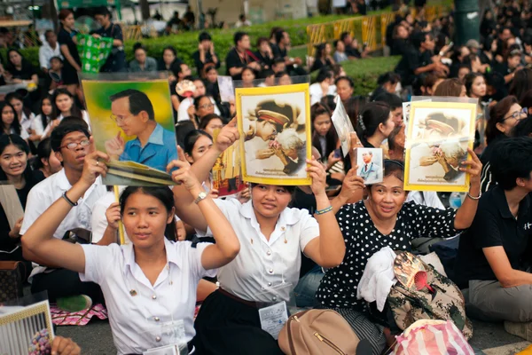 A Crowd holds images of king of Thailand.