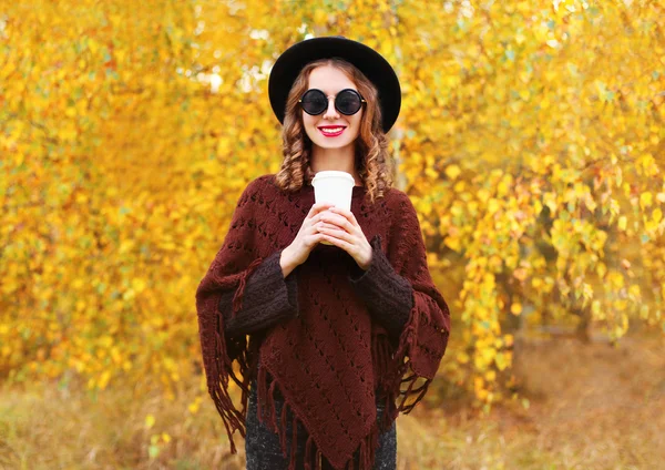 Fashion autumn pretty woman with coffee cup wearing a black hat
