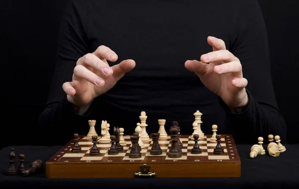 Closeup of a wooden chess board with chess figures and hands