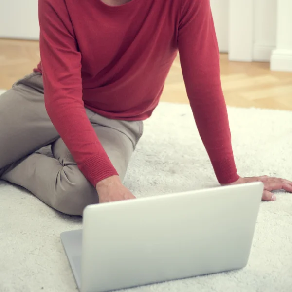 Young man sitting on floor with his laptop