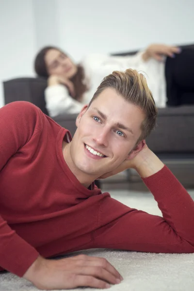 Blond man lying on carpet and woman sleeping on couch