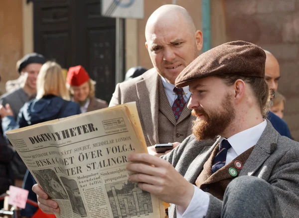 Two men reading vintage newspaper, wearing old fashioned tweed c