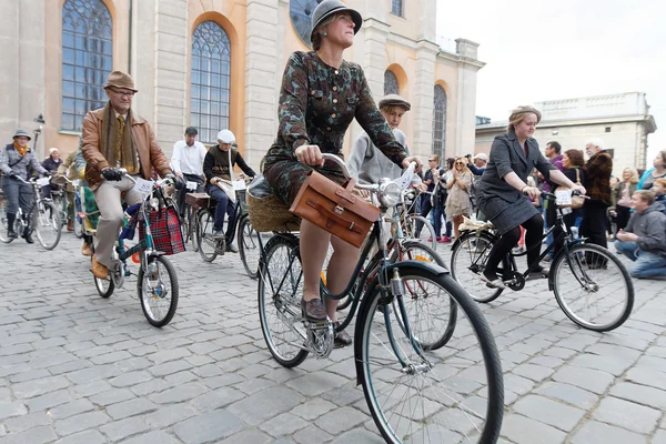 Cycling women and men dressed in old fashioned clothes