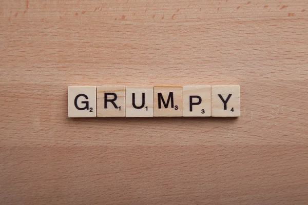Scrabble letters spelling the word grumpy.