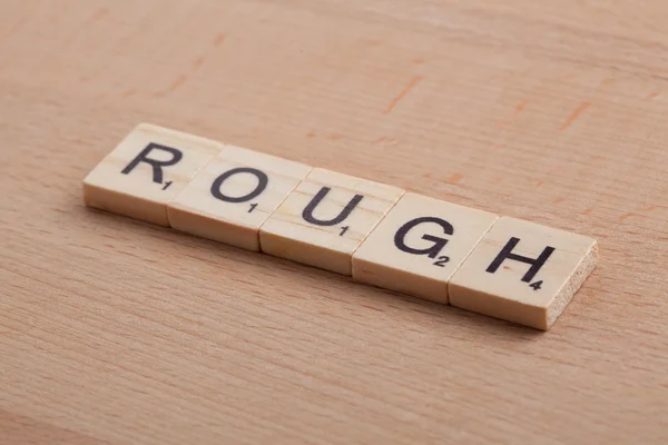 Scrabble letters spelling the word rough.