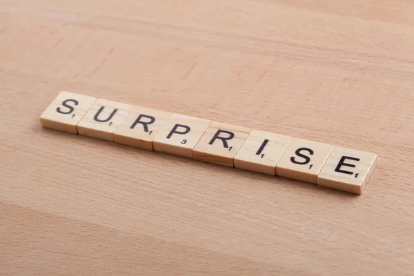 Scrabble letters spelling the word surprise.