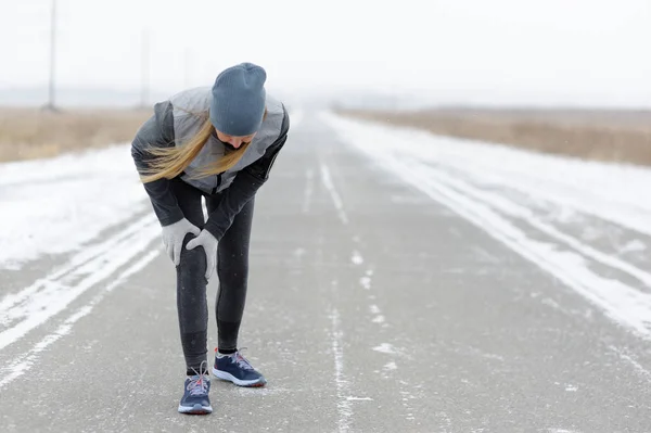 Injuries - sports running knee injury on woman. Winter marathon.