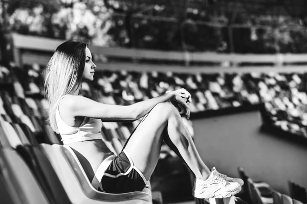Girl in shorts sitting on stadium