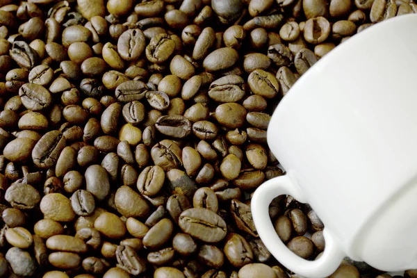 Roasted black coffee beans and white cup.