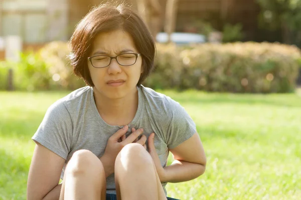 Asian glasses woman having heart attack.
