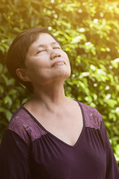 Asian senior woman relaxing and breathing fresh air.