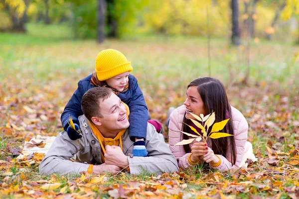 Family lying on the leaves autumn park