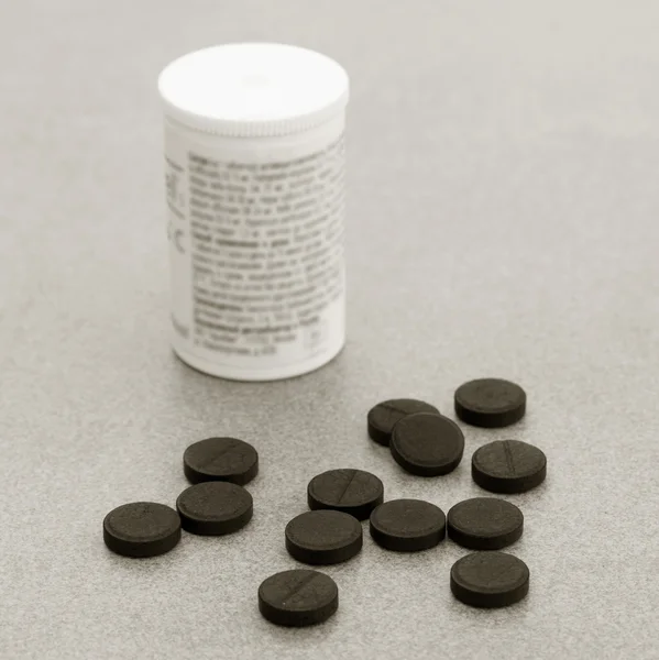 Activated Charcoal Tablets For Cleansing The Body On A Gray Background Closeup. Black And White Photo