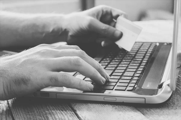 Man Hands holding credit card and using laptop. Online shopping, online banking and online marketing. shallow depth of field, black and white toning photo