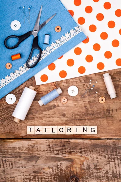 Tailoring background. Fabric for sewing, lace and accessories for needlework on old wooden table. Spool of thread, scissors, buttons, sewing supplies. Set for needlework