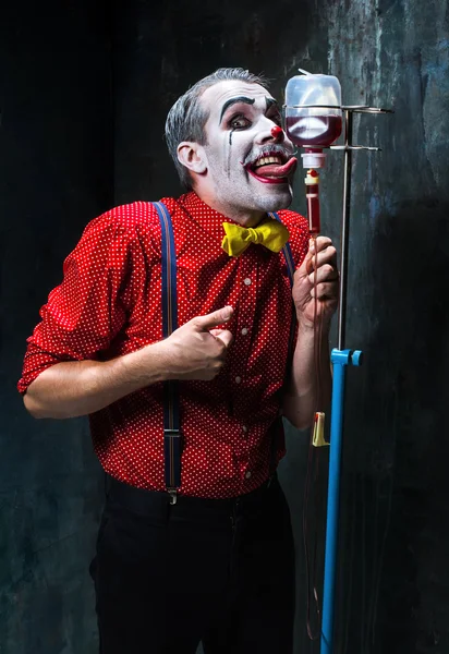 The scary clown and drip with blood on dack background. Halloween concept