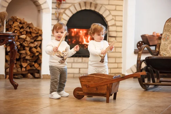 The two little girls standing at home against fireplace