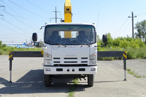 White Isuzu flatbed truck with yellow crane arm is in the parking lot - Russia, Moscow, 30 August 2016