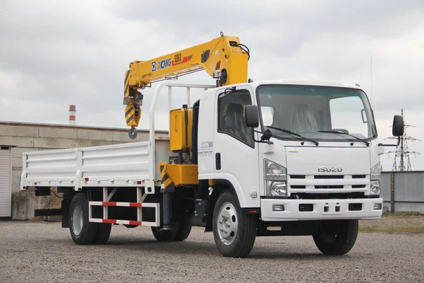 White Isuzu flatbed truck with yellow crane arm is in the parking lot - Russia, Moscow, 30 September 2016