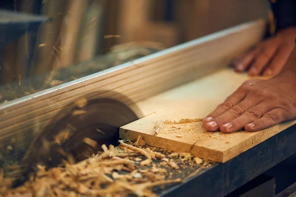 Carpenter cutting wooden plank