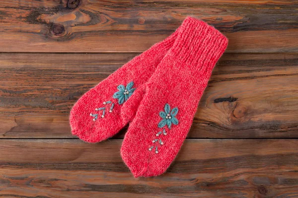 Red mittens on wooden background.
