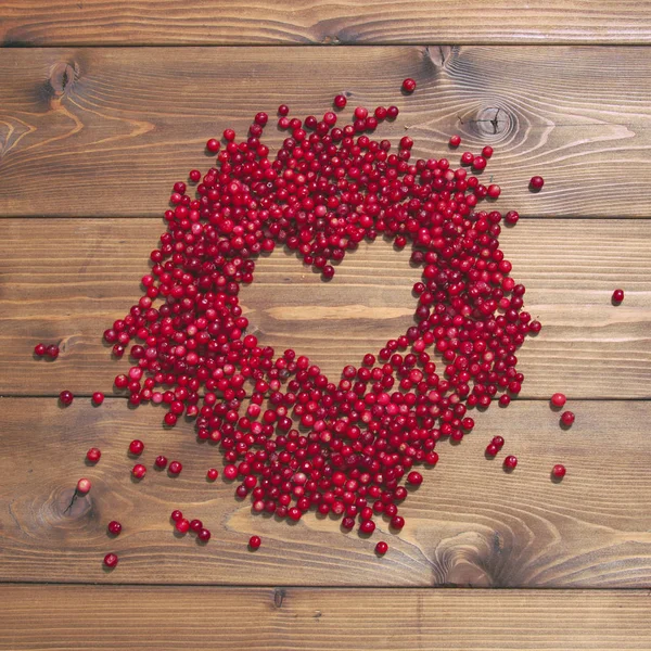 Cranberries on brown background. Heart frame.