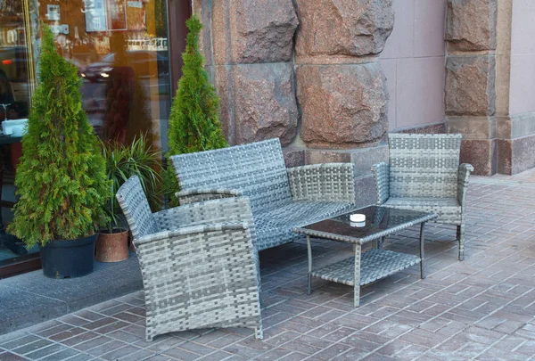 Wicker rattan furniture on pavement sidewalk cafe. Urban