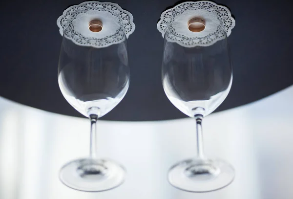 Wedding rings are covered with glasses for wine.