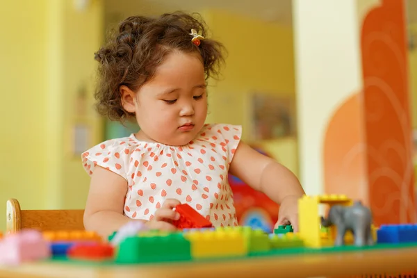 Kazakh curly girl playing in kids development center