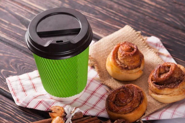 Cinnamon bun and coffee cup on wood background