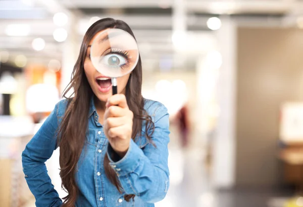 Surprised young woman with magnifying glass