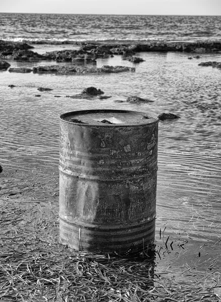Rusty oil barrel near the shore of the sea