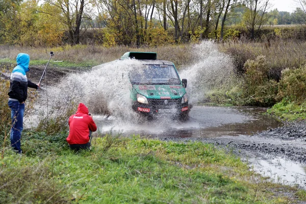 Sport 4wd vehicle boosts water hurdle surrounded by splashes.