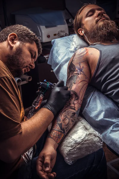 Professional tattooer at work in tatoo salon