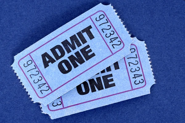 Pair of blue admit one movie tickets on a blue background.