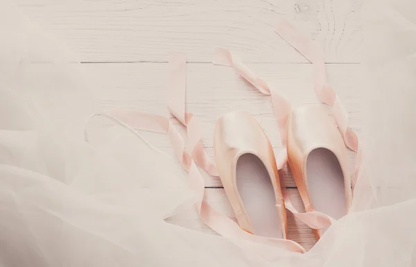 Pink ballet pointe shoes and tutu on white wood background