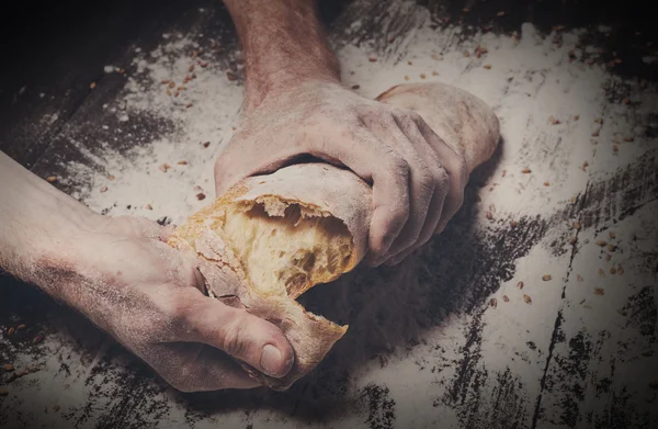 Bakery concept background. Hands breaking bread loaf