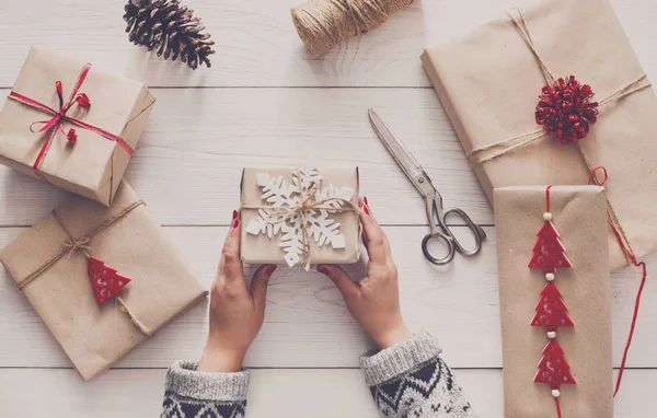 Womans hands wrapping christmas holiday present with craft twine