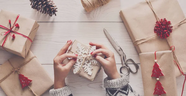 Womans hands wrapping christmas holiday present with craft twine