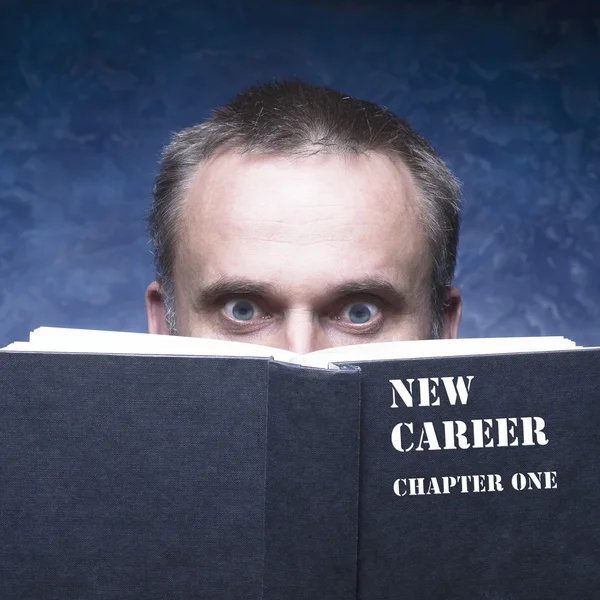 Your new chapter written on black book. Mature man behind book on blue background