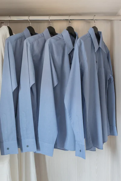 Row of blue color shirts hanging on rail