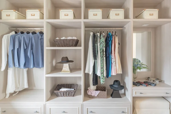 Modern wooden wardrobe with clothes hanging on rail in walk in c