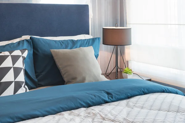 Modern blue color tone bedroom with lamp and vase of plant