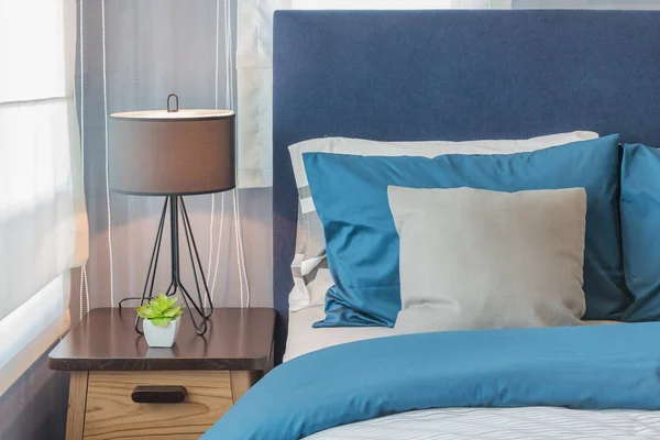 Modern blue color tone bedroom with lamp and vase of plant