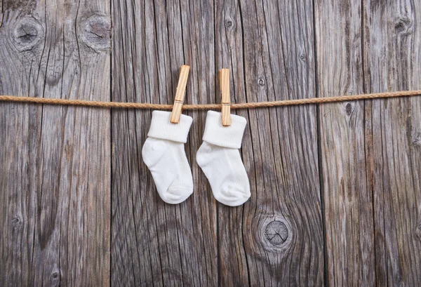 Baby goods hanging on the clothesline. Baby white socks on a clothespin