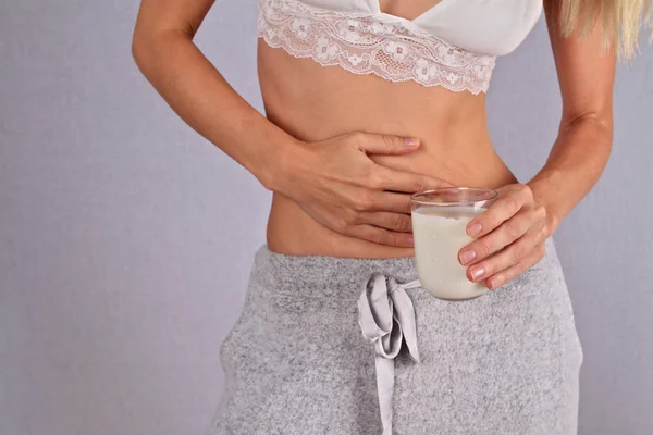 Woman with stomach pain holding a glass of milk. Dairy Intolerant person. Lactose intolerance, health care concept.