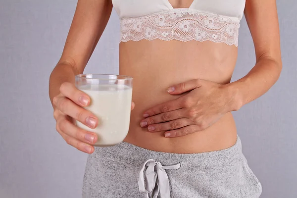 Woman with stomach pain holding a glass of milk. Dairy Intolerant person. Lactose intolerance, health care concept.
