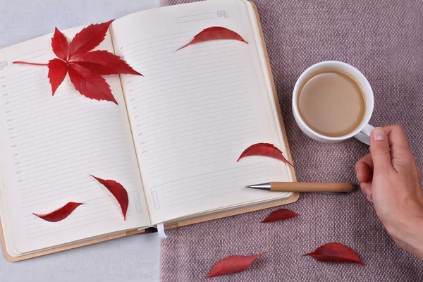 Autumn composition with cup of coffee, autumn leaves and and opened book open book with blank pages. Top view, flat lay, copy space